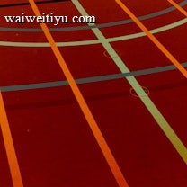 A sports court with intersecting lines in orange and blue, creating geometric patterns on a reddish-brown surface.